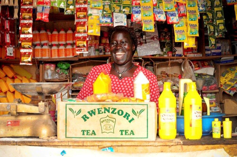 A smiling shopkeeper serving customers at a small general store counter
