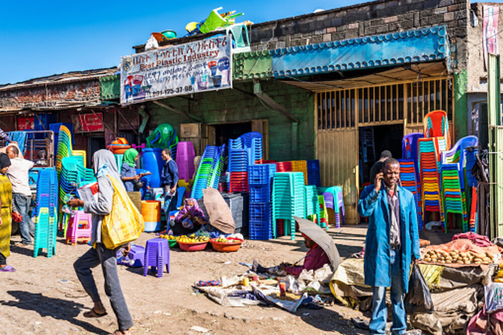 A busy outdoor market street lined with stalls of goods and traders