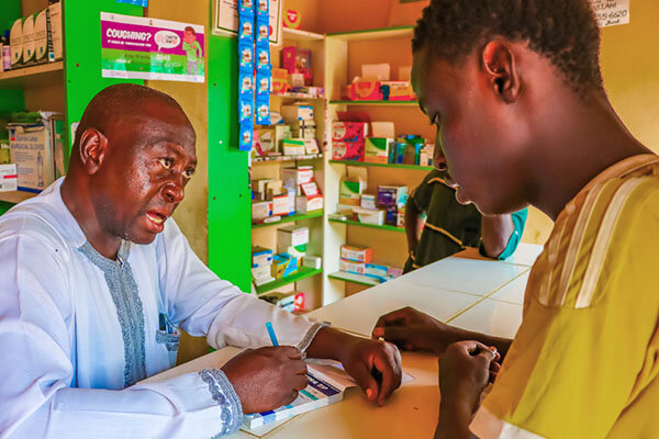A pharmacist explaining a product to a young customer at the counter